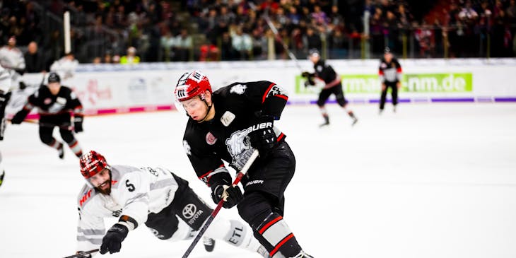 Dei giocatori di hockey che indossano divise da hockey e usano attrezzature da hockey durante una partita.