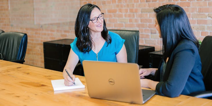 two women talking in front of computer