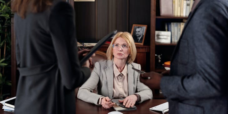 Personas en ropa formal alrededor de la mesa de conferencias en un despacho de abogados.