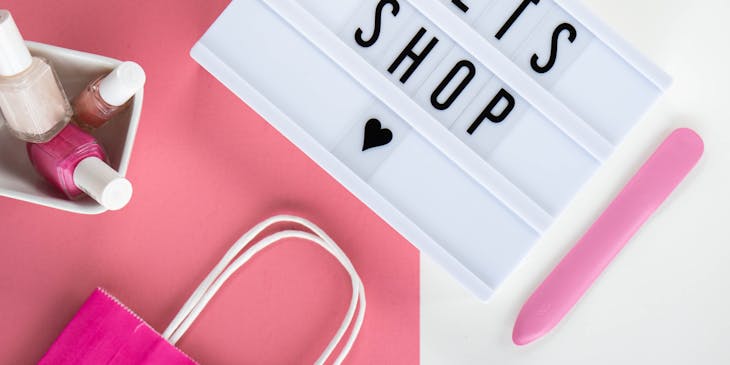 a sign next to nail polish on a pink and white background