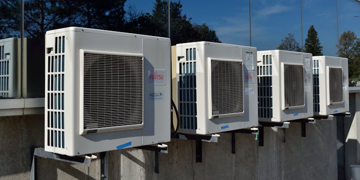 Una fila de unidades de aire acondicionado en el edificio de un negocio de climatización.