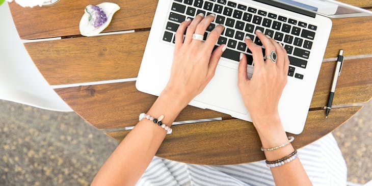 image taken from above of hands working on laptop keyboard