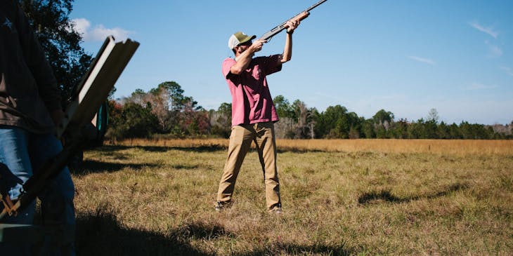 Hombre apuntando con su rifle en un campo de negocio de caza.