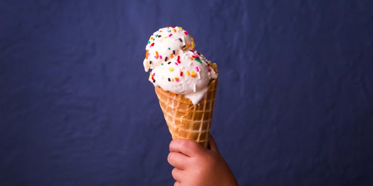 Un bambino con in mano un cono gelato ricoperto di praline colorate.