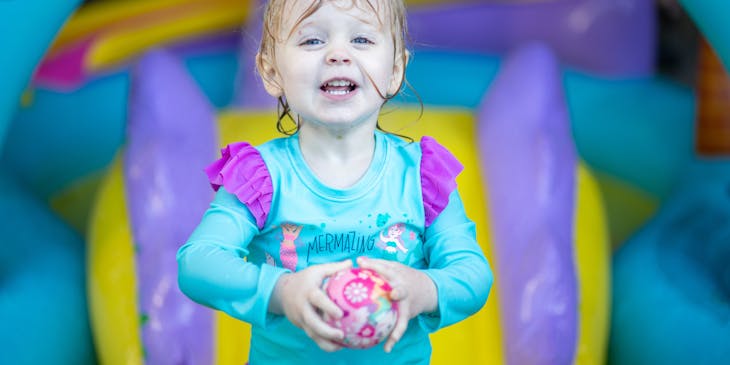 Menina segurando uma brinquedo em um parque indoor.