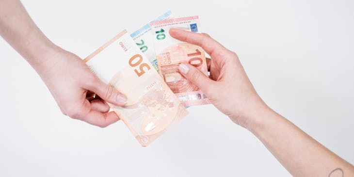 Close-up of two hands with money transacting an installment loan.