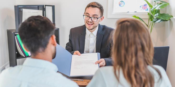 Um advogado entregando um contrato aos clientes em um escritório de advocacia.