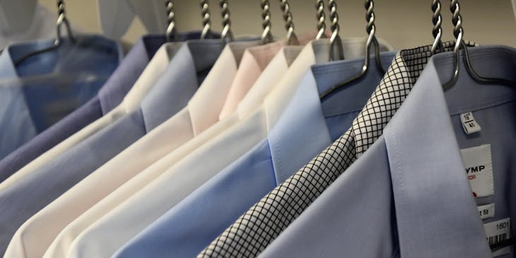 Camisas colgadas en ganchos en un negocio de ropa para hombre