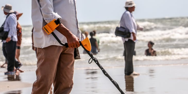 Hombre en la playa con un dispositivo de un negocio de detectores de metales.