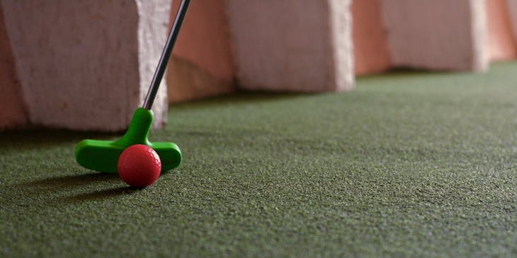 Une balle de golf rouge prête à être envoyée dans un trou de mini-golf.