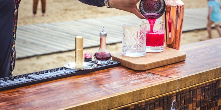 Un bartender sirviendo una bebida en la playa.