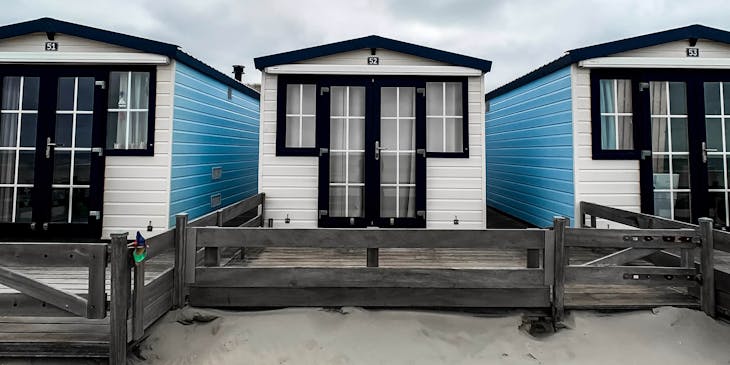 Des mobil-homes bleu et blanc sur le sable.