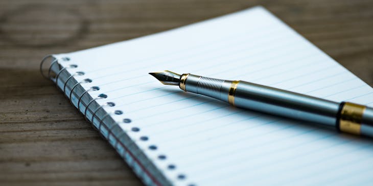 A notebook and fountain pen laid out ready to write a name change press release.