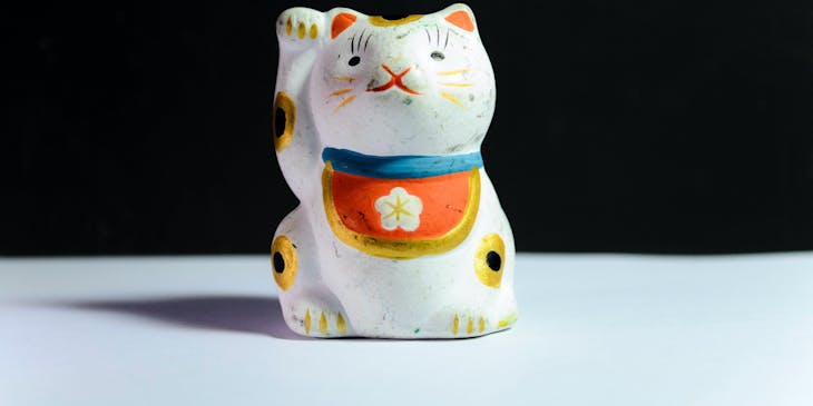 La figura de un gato de la buena suerte japonés en un negocio con nombre de suerte y fortuna