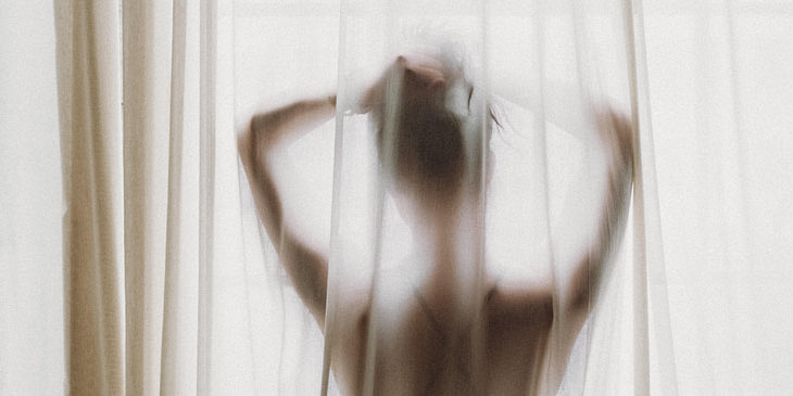 La silueta de una mujer posando frente a una ventana en un negocio erótico.