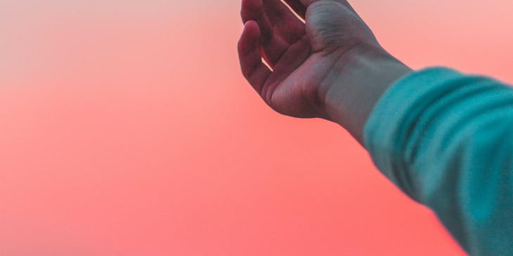 La mano de un hombre sosteniendo un foco con el cielo de fondo en una agencia de publicidad.