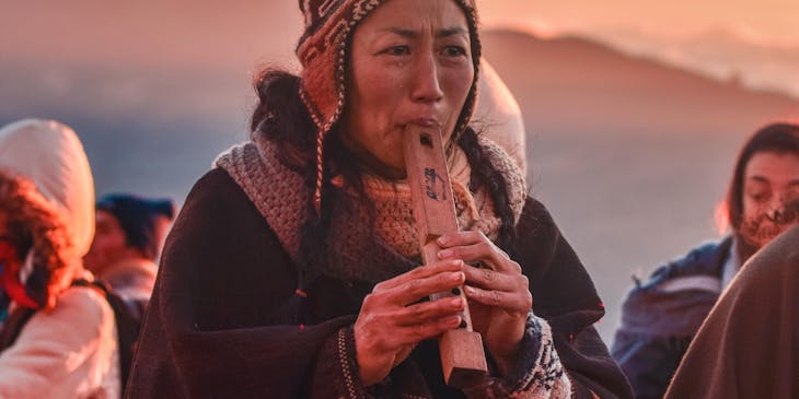 Una mujer tocando música típica de Bolivia en una agrupación boliviana.