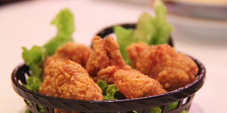 Un plato con piezas de pollo sobre una cama de lechuga en una broastería.