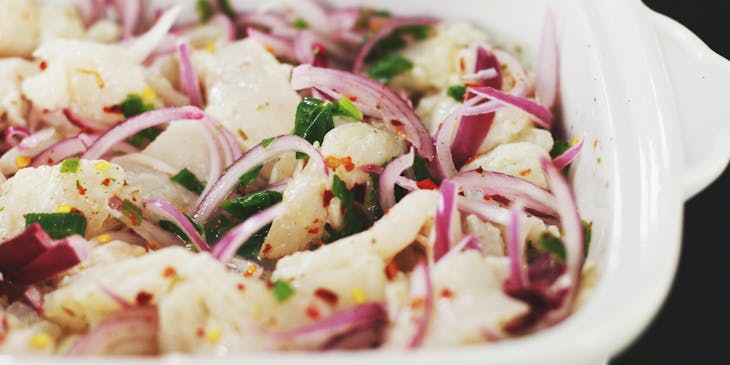 Un plato hondo y blanco con una porción generosa de ceviche en una cevichería.