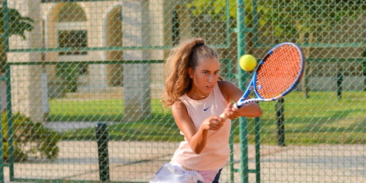 Una joven jugando tennis en un club de esparcimiento.