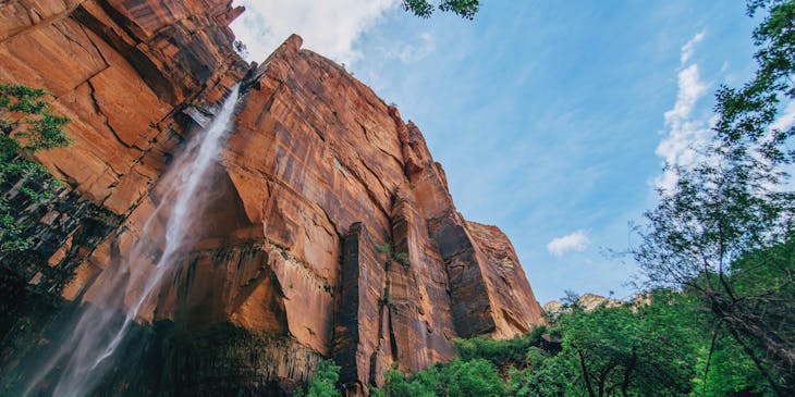 Paisaje de montaña con cascada y cielo claro en un emprendimiento natural.