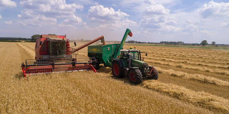 Un tractor rociando un químico de una empresa agroquímica en un campo.