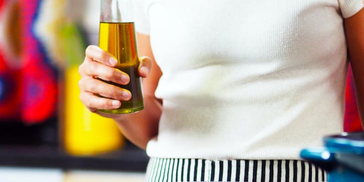 Una mujer sosteniendo una botella con aceite de soja en su mano derecha en una cocina dentro de una empresa de aceite de soja.