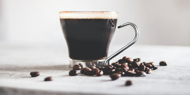 Una taza de café con granos de café a un lado en una empresa de café cubano.