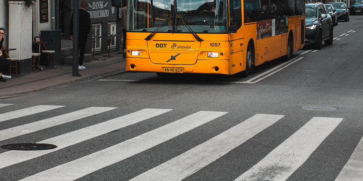 Un metrobús amarillo y negro, de una empresa de metrobuses, recogiendo pasajeros en una ciudad.