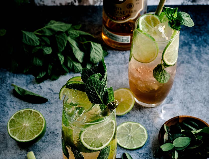 Dos vasos de ron con agua mineral, rodajas de limón y unas hojas de menta en el bar de una empresa de ron.
