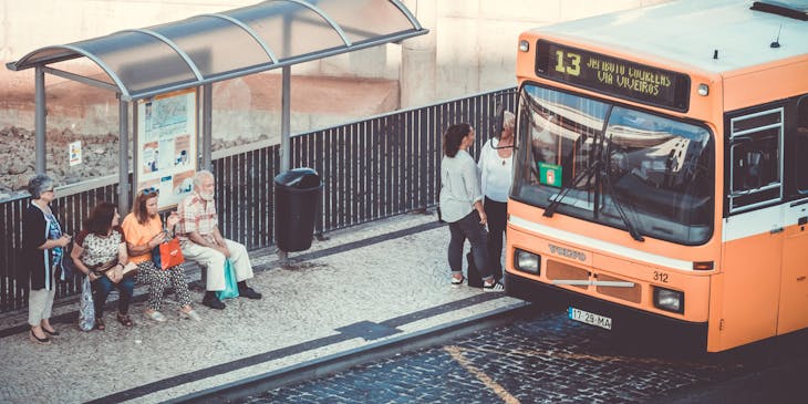 Personas subiéndose a un autobús naranja de una empresa de transporte colectivo.