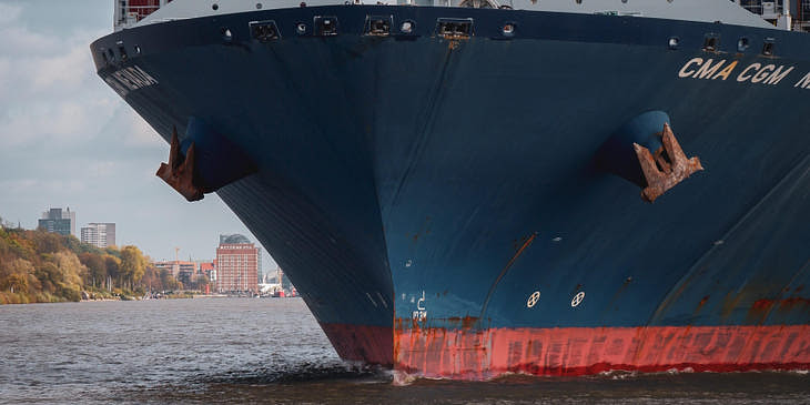 Un barco azul y rojode una empresa de transporte marítimo transportando productos a otras locaciones.