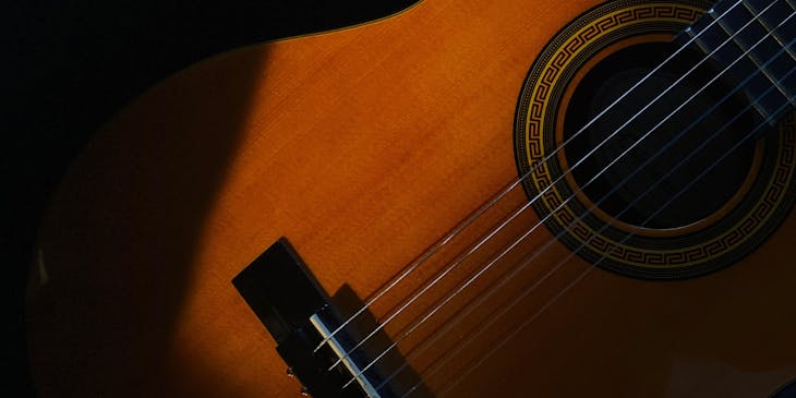 Una guitarra española entre sombras en un fondo negro en una escuela de cantaores.