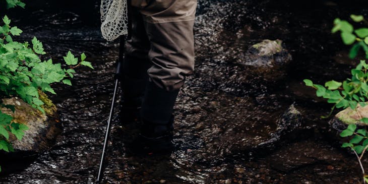 Un hombre maduro vestido con ropa adecuada para pescar y con su equipo de pesca, de parte de un grupo de pesca.