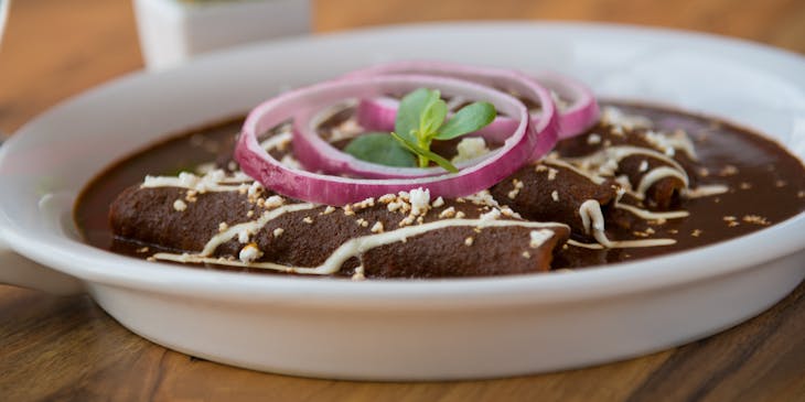 Un plato con enmoladas sobre una mesa de madera en un negocio de mole.