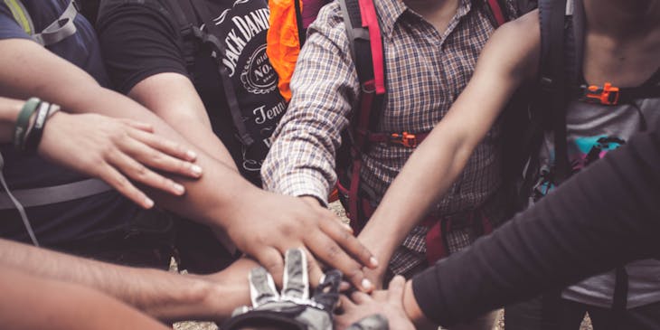 Un grupo de personas con las manos al centro haciendo un acuerdo en un negocio comunitario