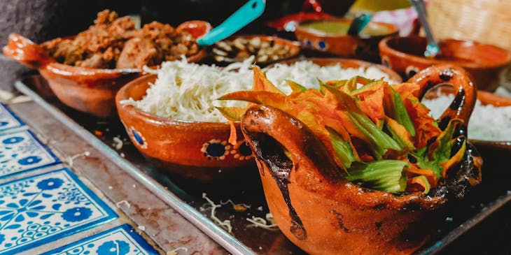 Antojitos mexicanos en cazuelas sobre una mesa cubierta con un delantal azul.