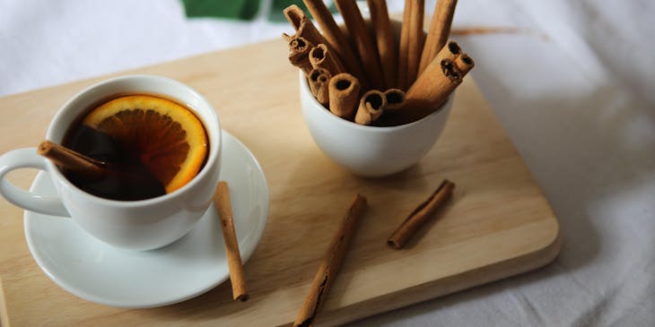 Taza de té con canelazo, lima y varitas de canela sobre una mesa de madera en un negocio de canelazo