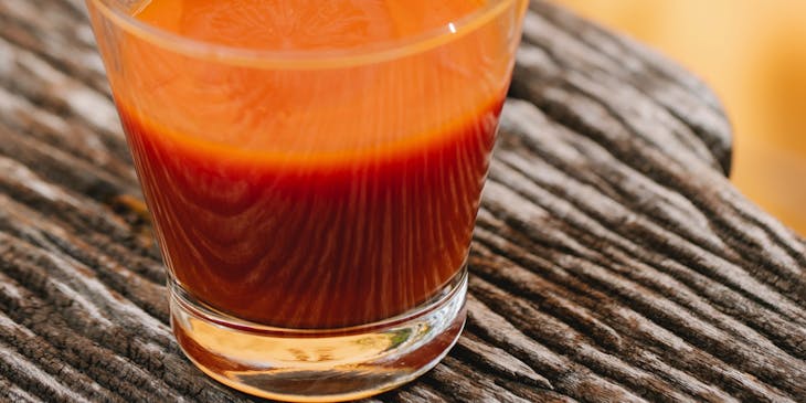 Un vaso de cristal con clamato y una rodaja de limón sobre una superficie de madera en un negocio de clamatos.