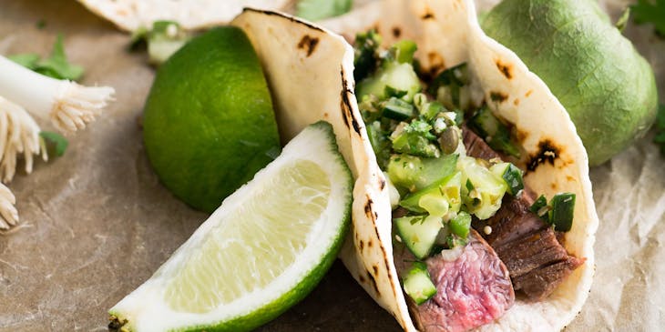 Tacos de carne asada con diversos complementos en un negocio de comida sonorense.