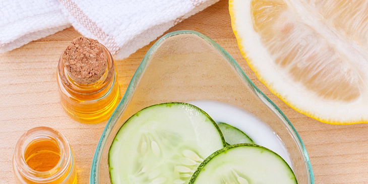 Rodajas de pepino dentro de un bowl junto a una mitad de lima, un frasco con miel y trozos de sábila en un negocio de cosméticos naturales.