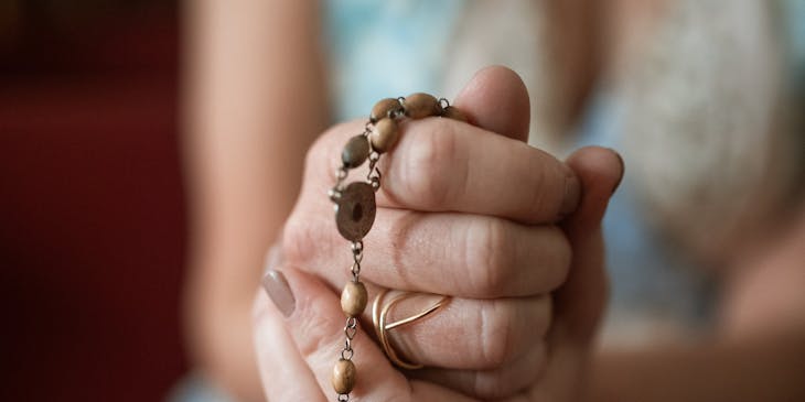 Una mujer tomando entre sus manos un escapulario en un negocio de escapularios