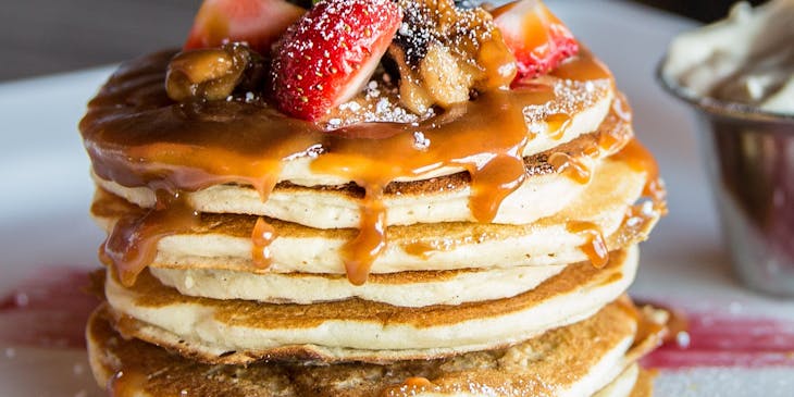 Un plato con hot cakes con cajeta, frutos rojos y crema batida en un negocio de hot cakes.