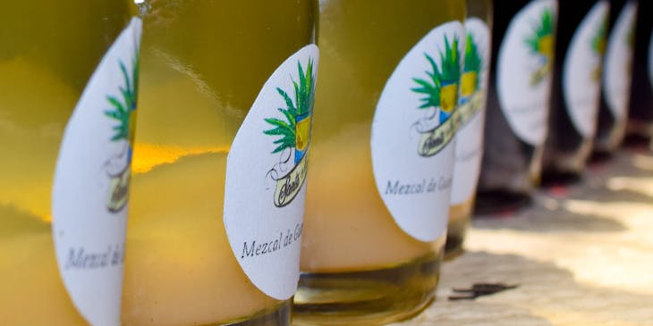 Botellas de mezcal en línea sobre una base de madera en un negocio de mezcal.