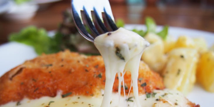 Una milanesa napolitana siendo comida por un comensal en un restaurante.