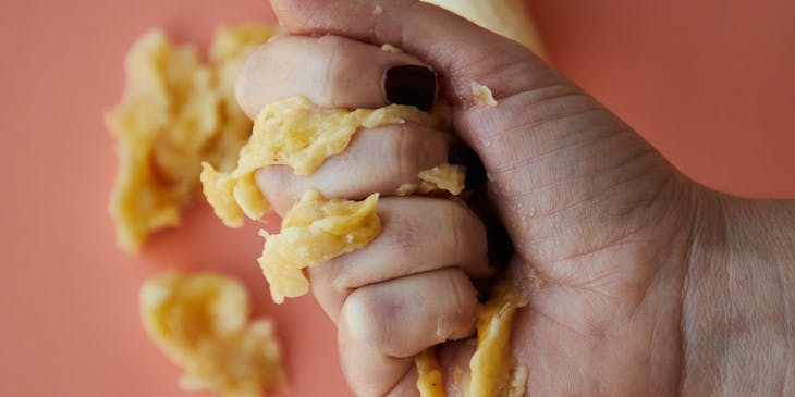 La mano de una persona aplastando un plátano en un negocio de mofongo.