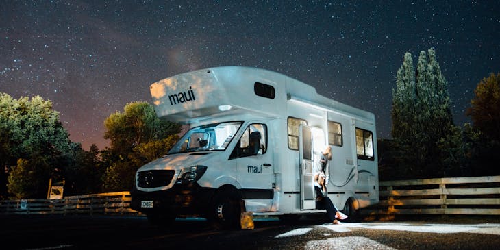 Una impresionante fotografía de una motorhome en medio de un espacio verde y recreativo en una noche estrellada.