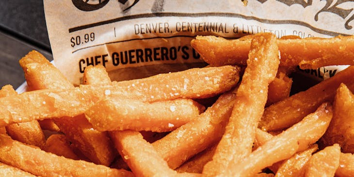 Un plato lleno de papas fritas con aderezo ranch en un negocio de papas fritas.