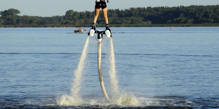 Una mujer montando un jetpack de un negocio de paseos en jetpack sobre un lago.