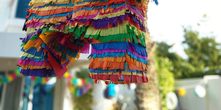 Una piñata de un animal fantástico de muchos colores fuera de un negocio de piñatas.